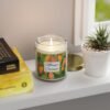 mango coconut lit candle clear jar sitting on shelf